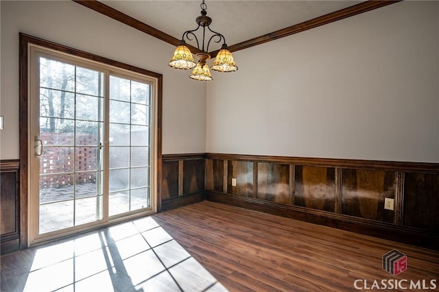 unfurnished room with hardwood / wood-style flooring, ornamental molding, and an inviting chandelier