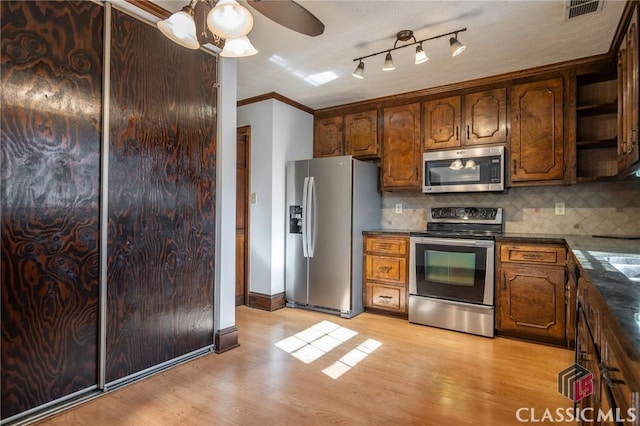 kitchen with tasteful backsplash, appliances with stainless steel finishes, and light hardwood / wood-style flooring