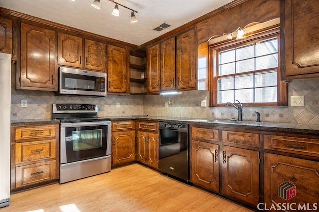 kitchen with tasteful backsplash, sink, light hardwood / wood-style flooring, and stainless steel appliances