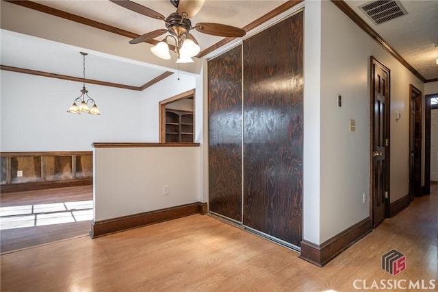 interior space with crown molding, ceiling fan with notable chandelier, and light wood-type flooring