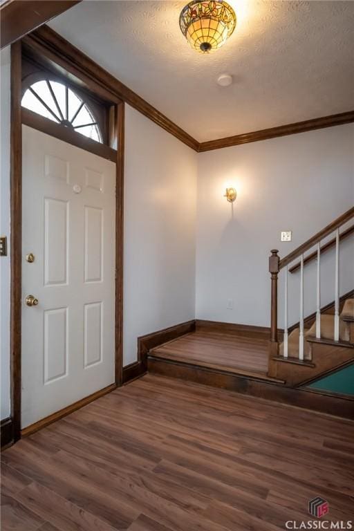 entryway with crown molding, dark hardwood / wood-style floors, and a textured ceiling