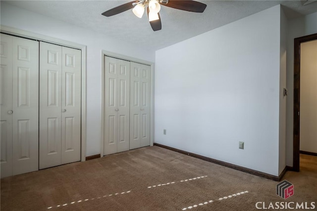 unfurnished bedroom featuring multiple closets, light colored carpet, ceiling fan, and a textured ceiling