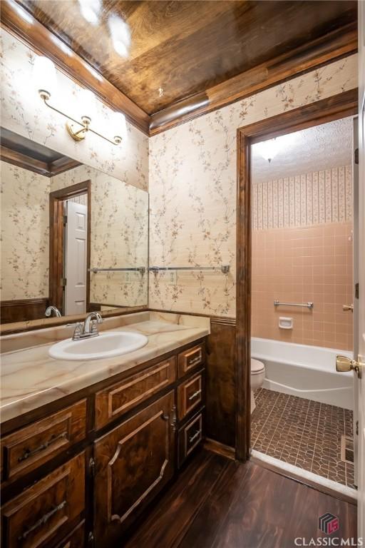 full bathroom featuring hardwood / wood-style flooring, vanity, toilet, and crown molding