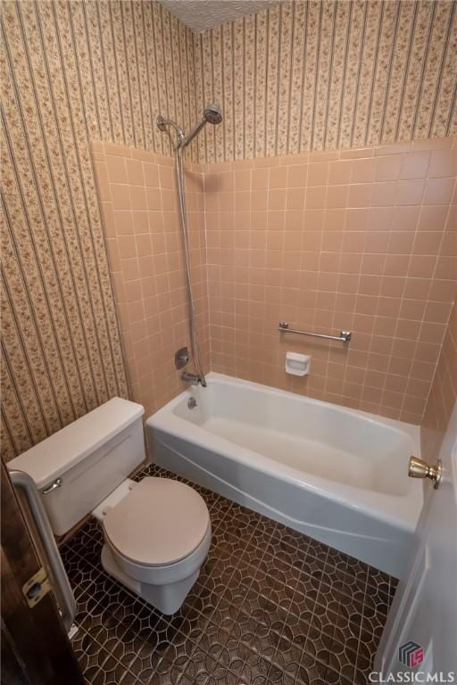 bathroom with tile patterned flooring, tiled shower / bath combo, and toilet