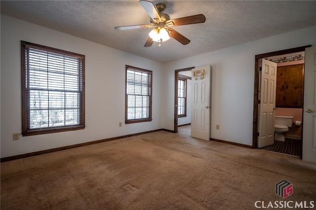 unfurnished bedroom with ceiling fan, ensuite bathroom, carpet flooring, and a textured ceiling