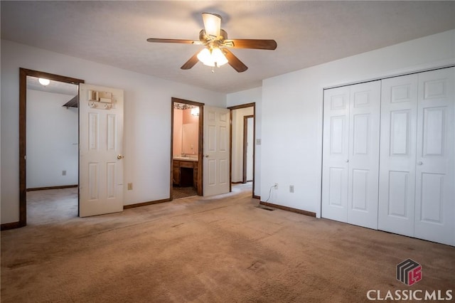 unfurnished bedroom with ceiling fan, light colored carpet, ensuite bathroom, and a closet