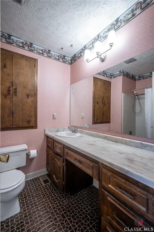 bathroom with vanity, toilet, a textured ceiling, and walk in shower