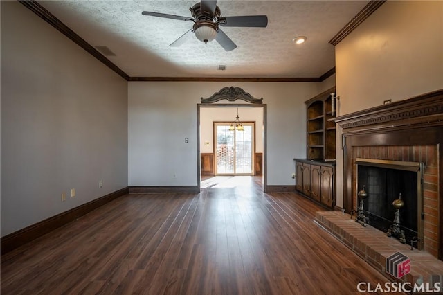 unfurnished living room with dark wood-type flooring, a brick fireplace, a textured ceiling, ornamental molding, and ceiling fan