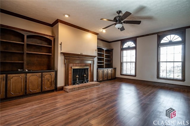 unfurnished living room with a brick fireplace, crown molding, dark wood-type flooring, and a textured ceiling