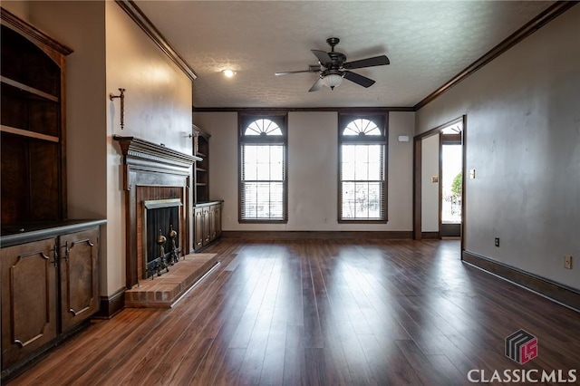 unfurnished living room featuring crown molding, ceiling fan, dark hardwood / wood-style floors, a fireplace, and a textured ceiling