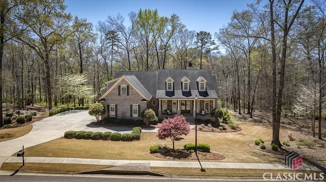 cape cod house with covered porch and a front lawn