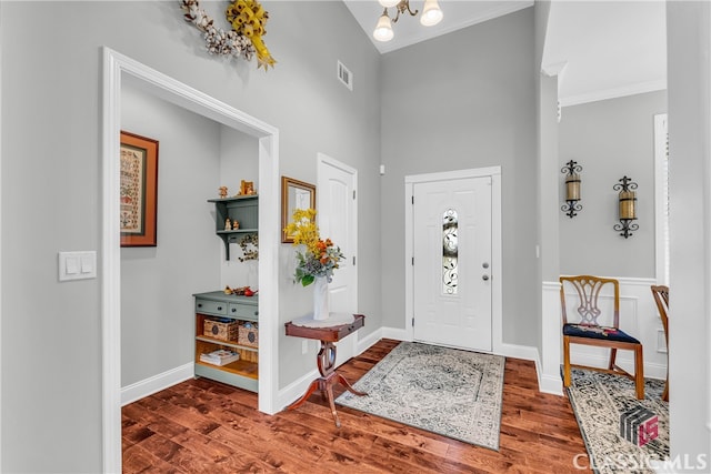 entryway with crown molding, dark hardwood / wood-style floors, and an inviting chandelier