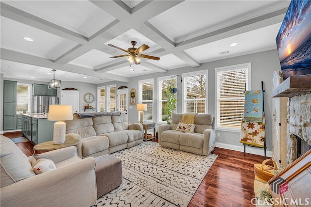 living room with hardwood / wood-style flooring, a stone fireplace, coffered ceiling, and beamed ceiling