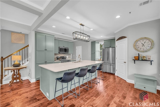 kitchen featuring sink, decorative light fixtures, appliances with stainless steel finishes, a kitchen breakfast bar, and a kitchen island with sink