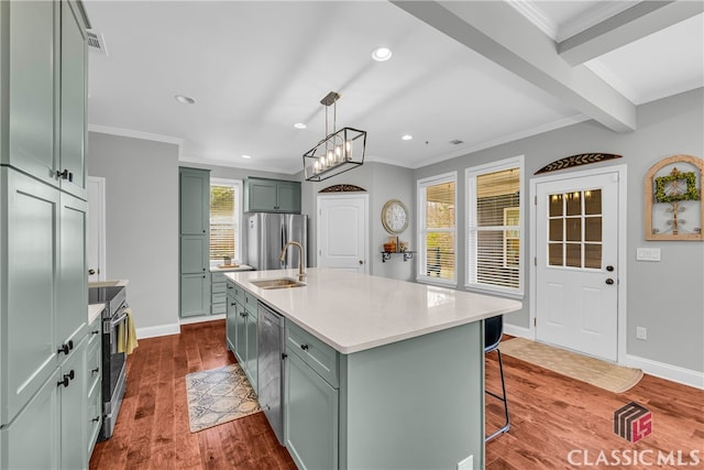 kitchen featuring appliances with stainless steel finishes, decorative light fixtures, sink, hardwood / wood-style flooring, and a center island with sink