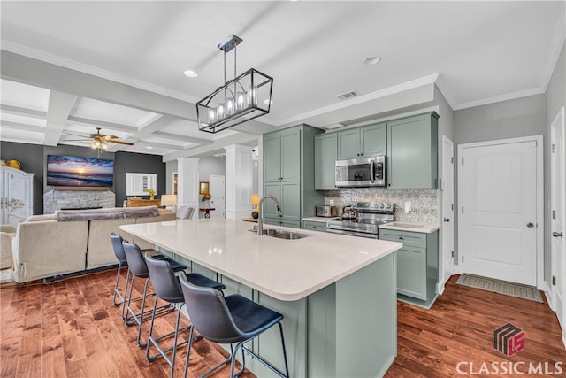 kitchen featuring sink, appliances with stainless steel finishes, hanging light fixtures, a kitchen breakfast bar, and an island with sink