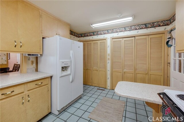 kitchen featuring light tile patterned flooring, light brown cabinets, and white fridge with ice dispenser