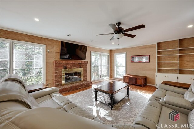 living room featuring a brick fireplace, light hardwood / wood-style floors, and ceiling fan