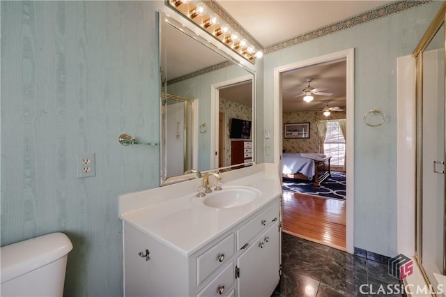 bathroom with a shower with shower door, vanity, ornamental molding, ceiling fan, and toilet