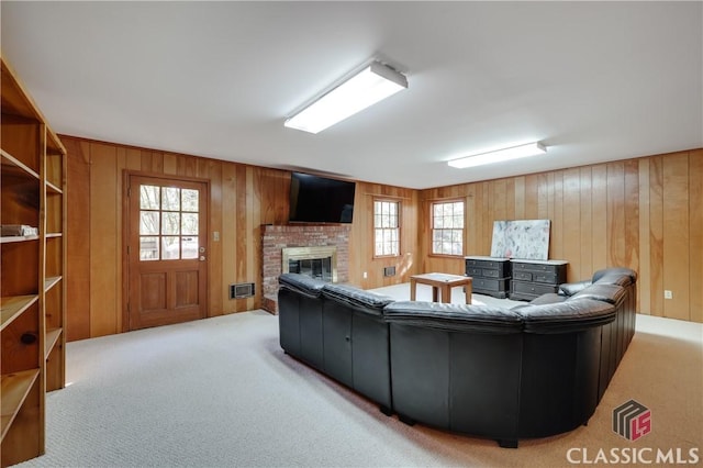 living room featuring a brick fireplace, carpet floors, a wealth of natural light, and wood walls