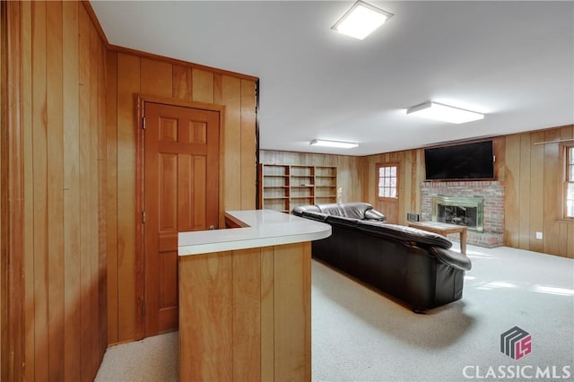 carpeted living room featuring a fireplace and wood walls