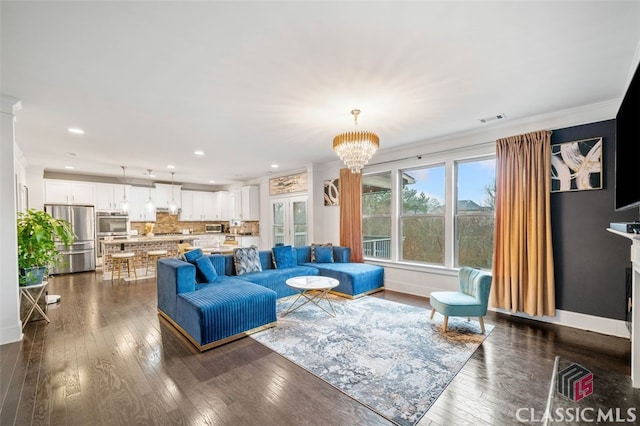 living room featuring crown molding, a chandelier, and dark wood-type flooring