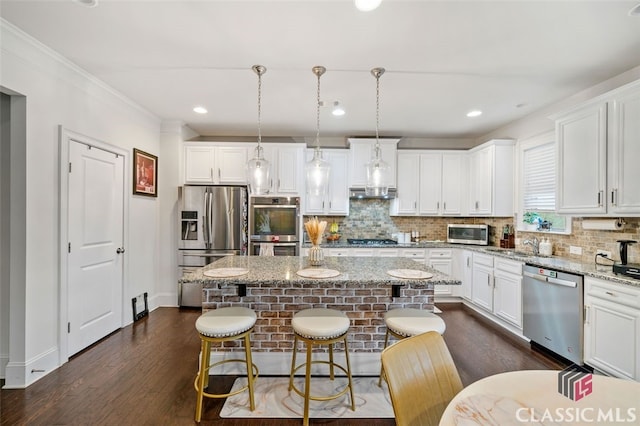 kitchen featuring a center island, pendant lighting, stainless steel appliances, and light stone counters