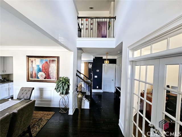 interior space with a towering ceiling, dark wood-type flooring, and ornamental molding