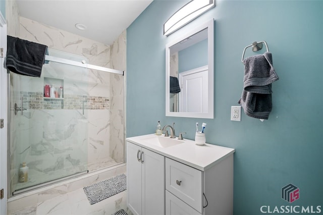 bathroom featuring a shower with door and vanity