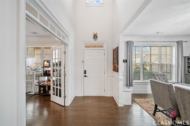 foyer entrance featuring dark wood-type flooring, a high ceiling, and crown molding