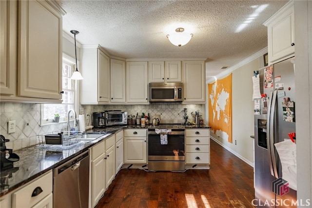 kitchen featuring decorative light fixtures, sink, dark stone countertops, stainless steel appliances, and crown molding