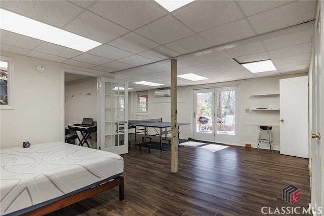 bedroom featuring french doors, a paneled ceiling, dark hardwood / wood-style flooring, and a wall unit AC