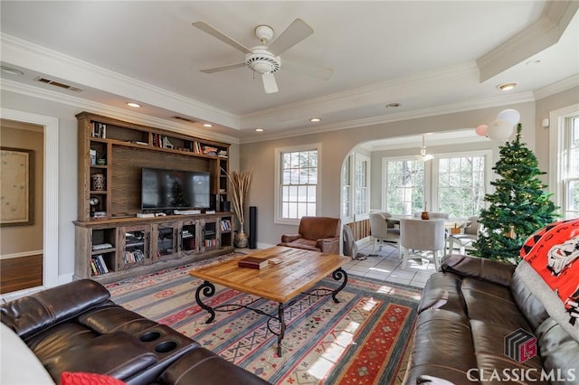 living room featuring crown molding, ceiling fan, a raised ceiling, and light tile patterned floors