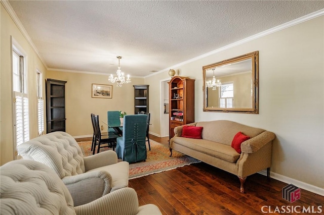 living room with ornamental molding, dark hardwood / wood-style floors, a notable chandelier, and a textured ceiling