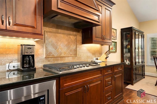 kitchen featuring lofted ceiling, premium range hood, stainless steel appliances, dark hardwood / wood-style flooring, and decorative backsplash