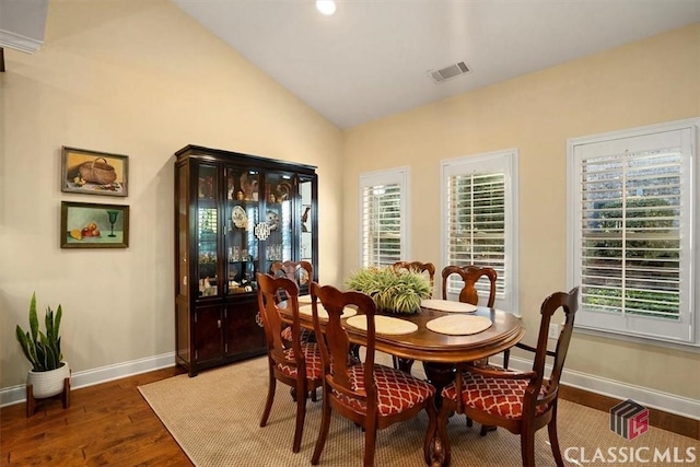 dining room with lofted ceiling and dark wood-type flooring