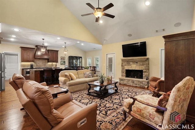 living room featuring ceiling fan, high vaulted ceiling, a fireplace, and hardwood / wood-style floors