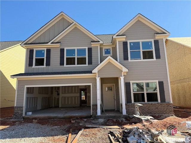 view of front of home with brick siding, board and batten siding, driveway, and a garage