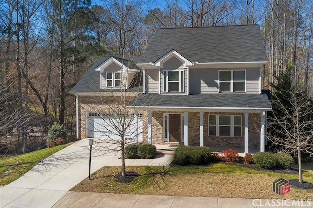 view of front of home featuring brick siding, covered porch, a front yard, a garage, and driveway