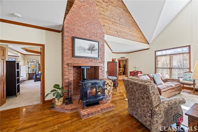 living room featuring crown molding, high vaulted ceiling, hardwood / wood-style floors, and a wood stove