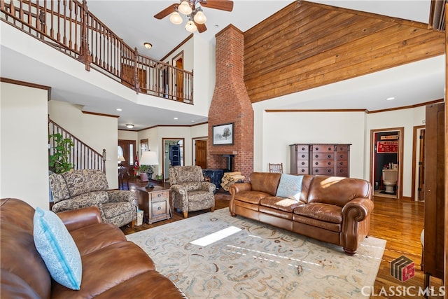 living room featuring ceiling fan, ornamental molding, a high ceiling, and light wood-type flooring