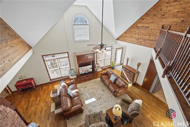 living room with hardwood / wood-style flooring, ceiling fan, and high vaulted ceiling