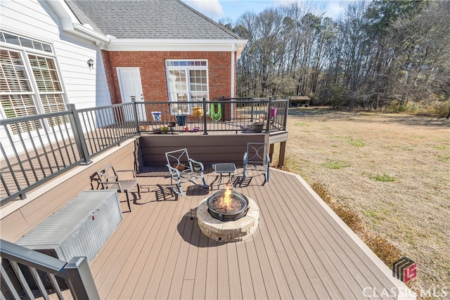 wooden deck featuring a yard and a fire pit