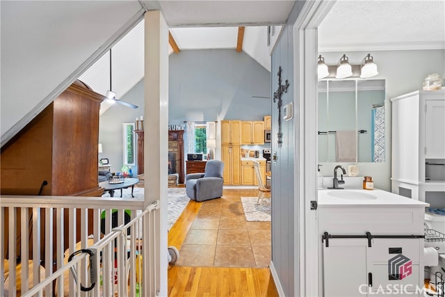 bathroom featuring ceiling fan, tile patterned flooring, high vaulted ceiling, vanity, and a fireplace