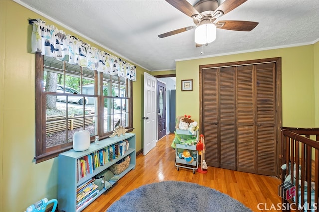 bedroom featuring crown molding, a textured ceiling, a closet, ceiling fan, and hardwood / wood-style floors