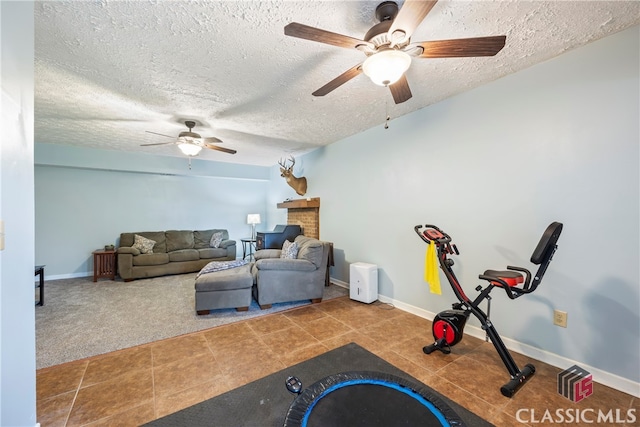 workout room with ceiling fan, light colored carpet, and a textured ceiling