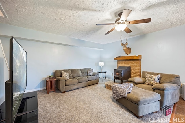 living room featuring ceiling fan, a textured ceiling, carpet, and a wood stove