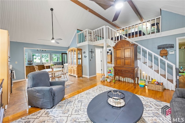 living room with beam ceiling, high vaulted ceiling, ceiling fan, and light hardwood / wood-style flooring