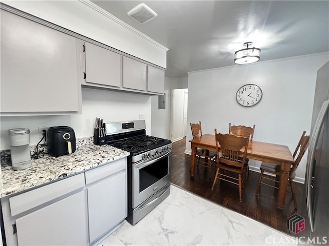 kitchen with crown molding, light stone counters, and stainless steel gas stove