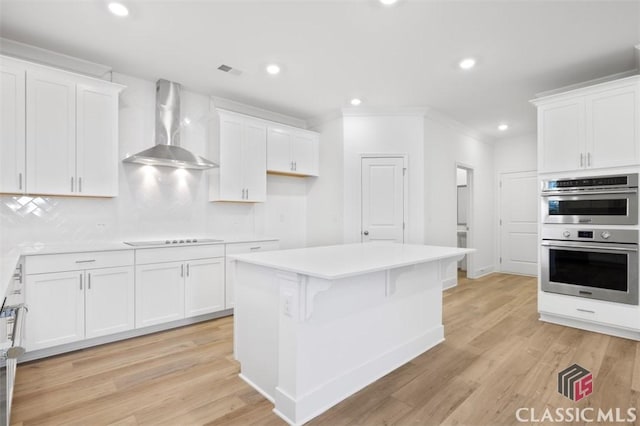 kitchen with white cabinetry and wall chimney range hood